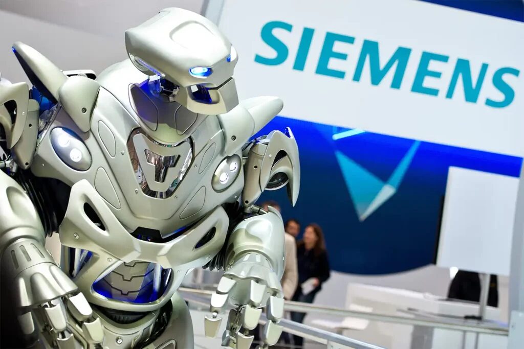 A close up of Titan the Robot in front of a large Siemens logo on their trade show stand.
